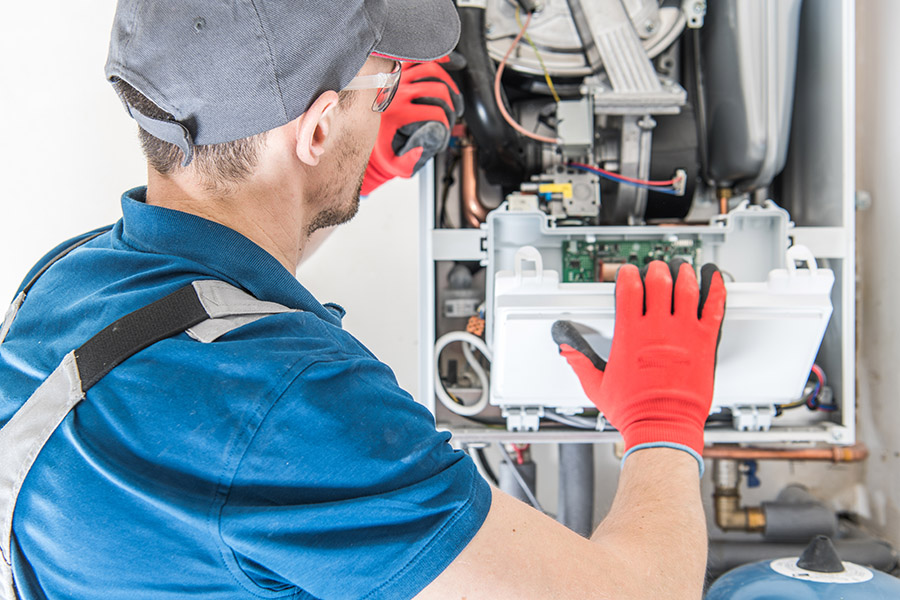 Technician repairing a gas furnace Technician repairing a gas furnace