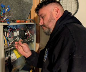 A Kasper Mechanical technician inspecting electrical components of a furnace.